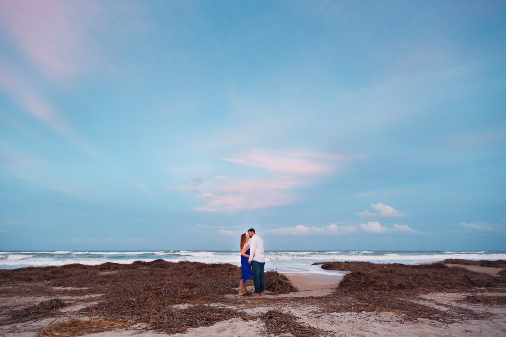 couple kissing on beach engagement photos at sunset